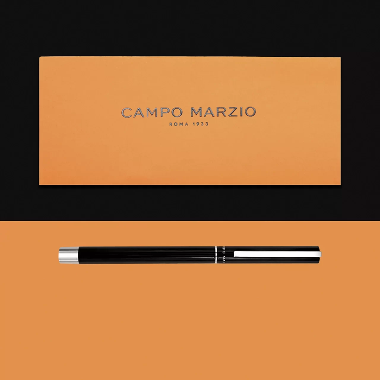 an orange rectangular campo marzio pen case and a black ballpoint pen with silver details that they have a black and orange background
