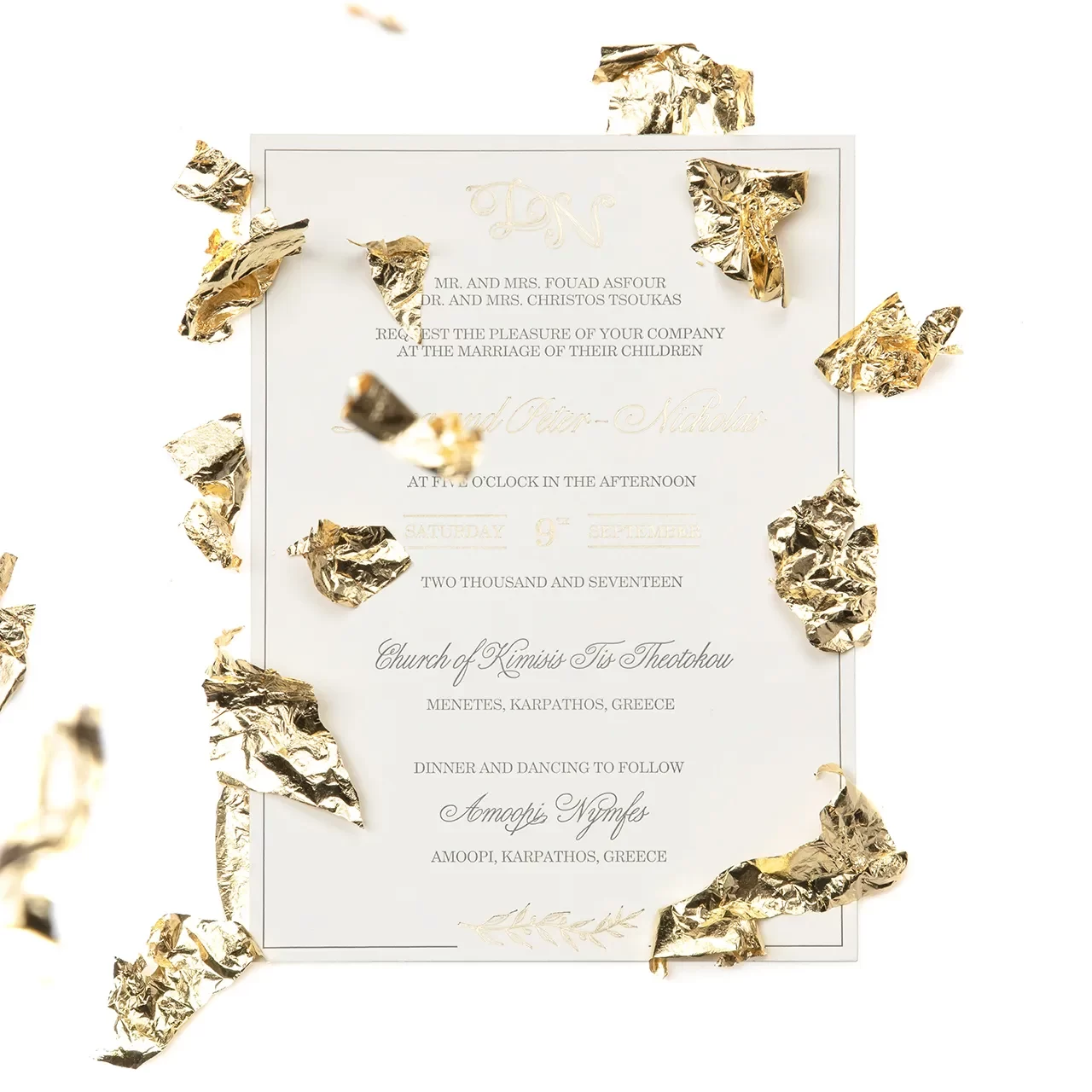 a beige paper invitation with gold and black writings on it and golden leaves flying around it and on top of it