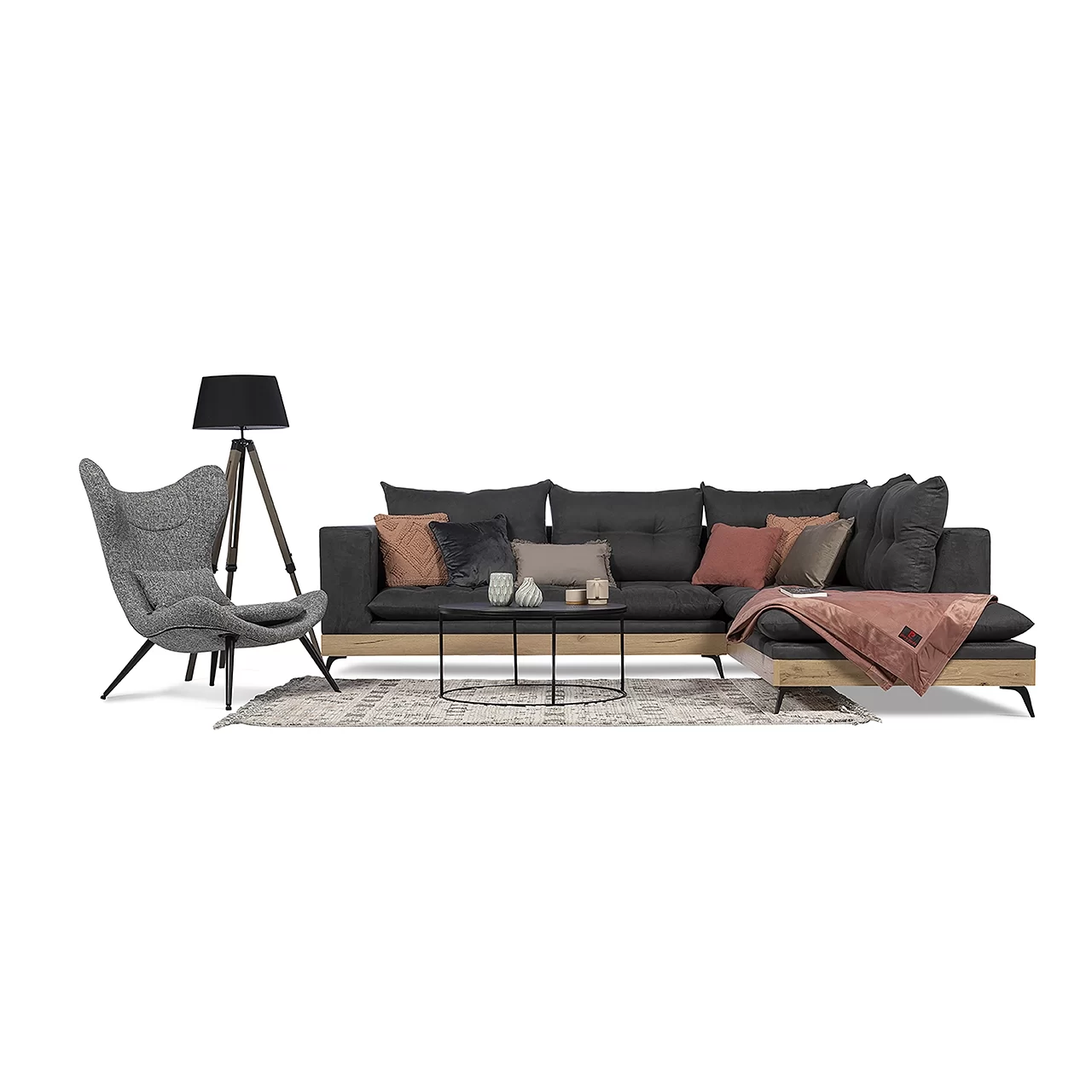 a grey armchair with behind it a lamb and beside it a black sectional couch sofa with multi color pillows and a small table in front of the sofa