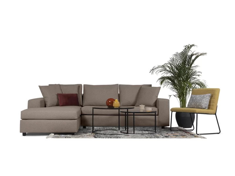 a beige couch with a table in fron of it and beside the couch is a chair and behind it a plant