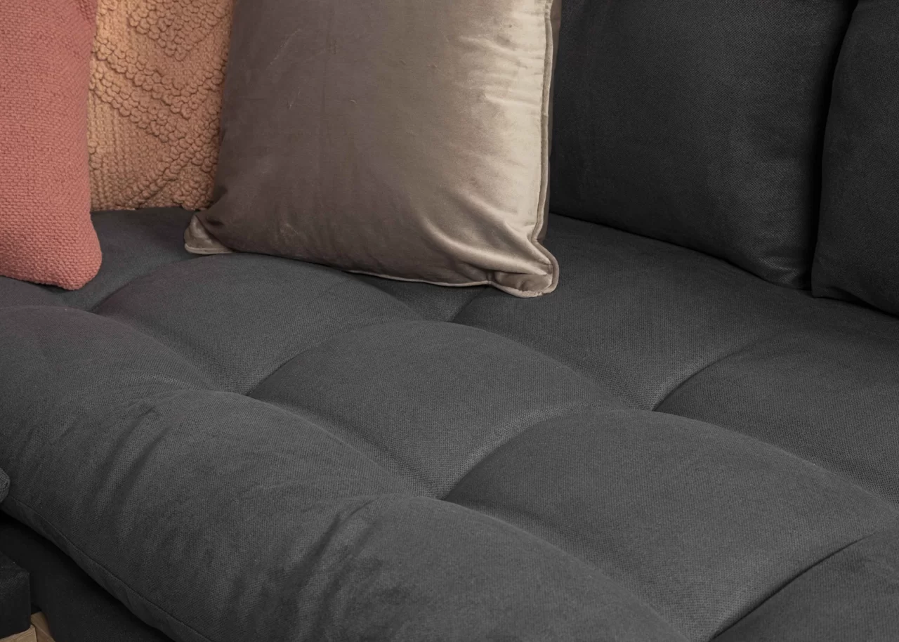 a close up shot of a black couch and three pillows on the side of the couch