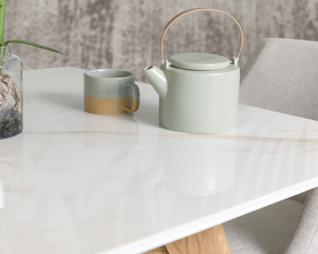 a close up shot of a white marbled coffee table that on top of it has mint coloured kettle and a mug