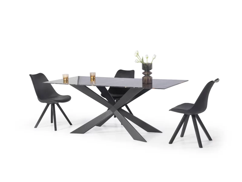 A reflective black table surrounded by 3 black chairs and a plant on top of the table